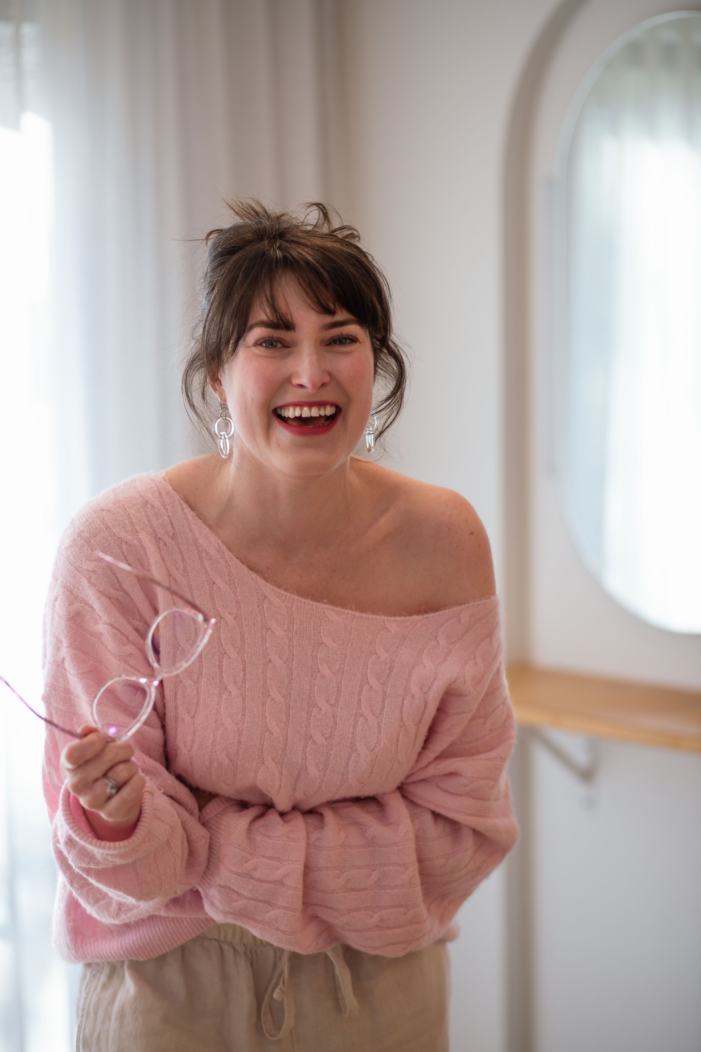 Amélie smiling in a soft pink knit
