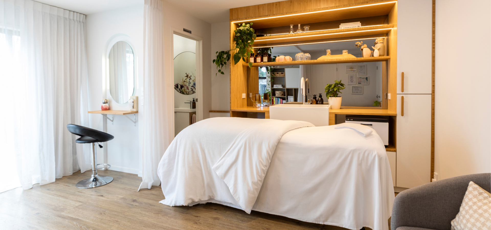 A treatment bed in The Cocoon dressed in crisp white linen, framed by soft natural light.