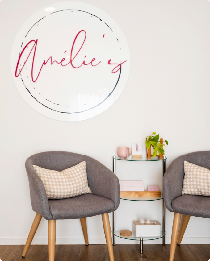Two upholstered armchairs beside a small trolley under a round Amélie's mirror.