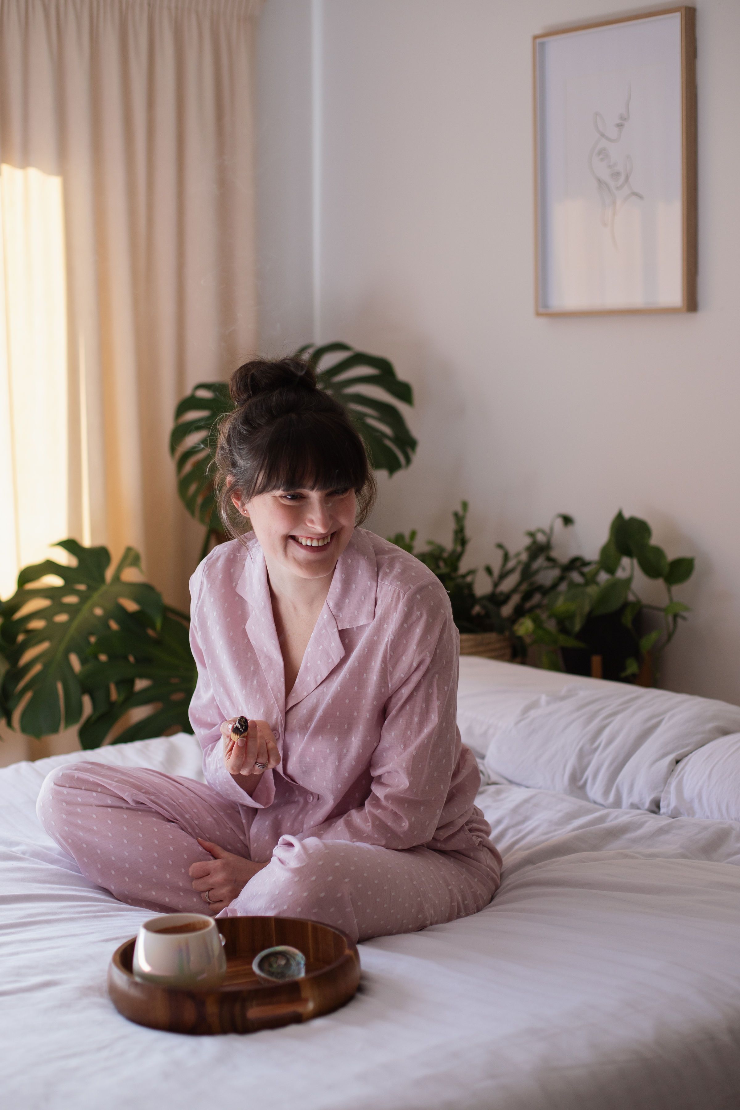 A woman resting in soft pink loungewear, at ease in a calm, sunlit room.