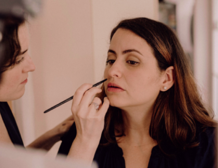Amélie applying lip colour with a brush during a one-to-one makeup session.