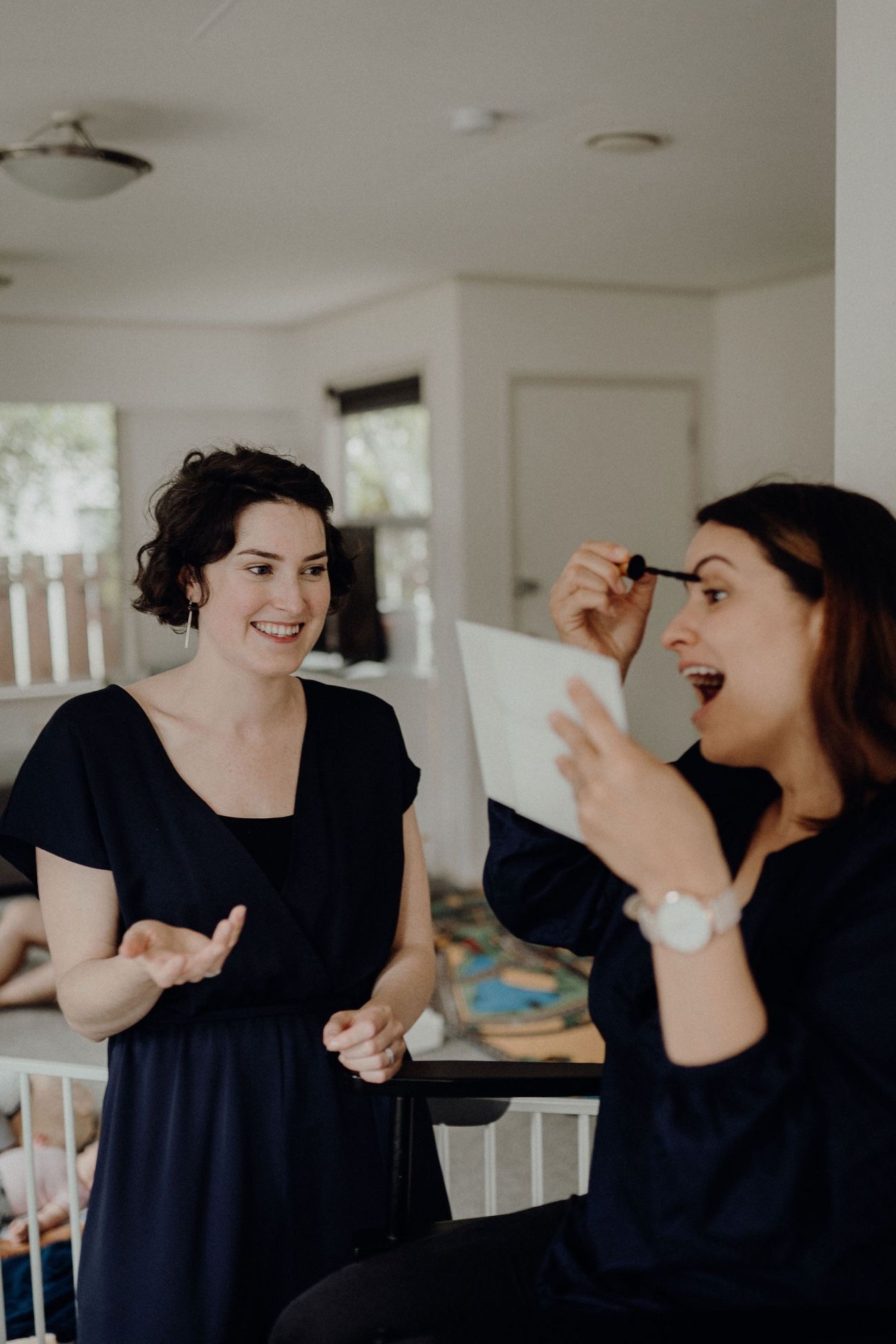 A client applying mascara with a hand mirror while Amélie guides her through a one-to-one makeup lesson.